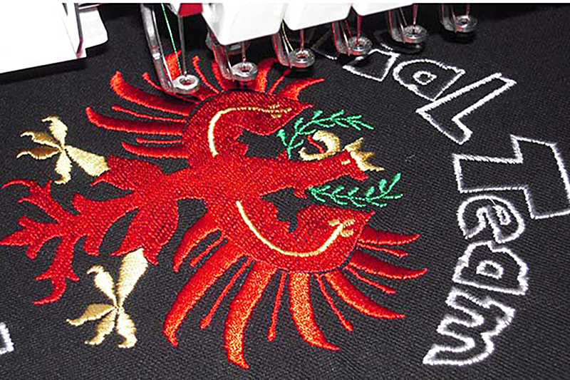 Stickmaschine bestickt ein Polohemd mit dem Tiroler Adler